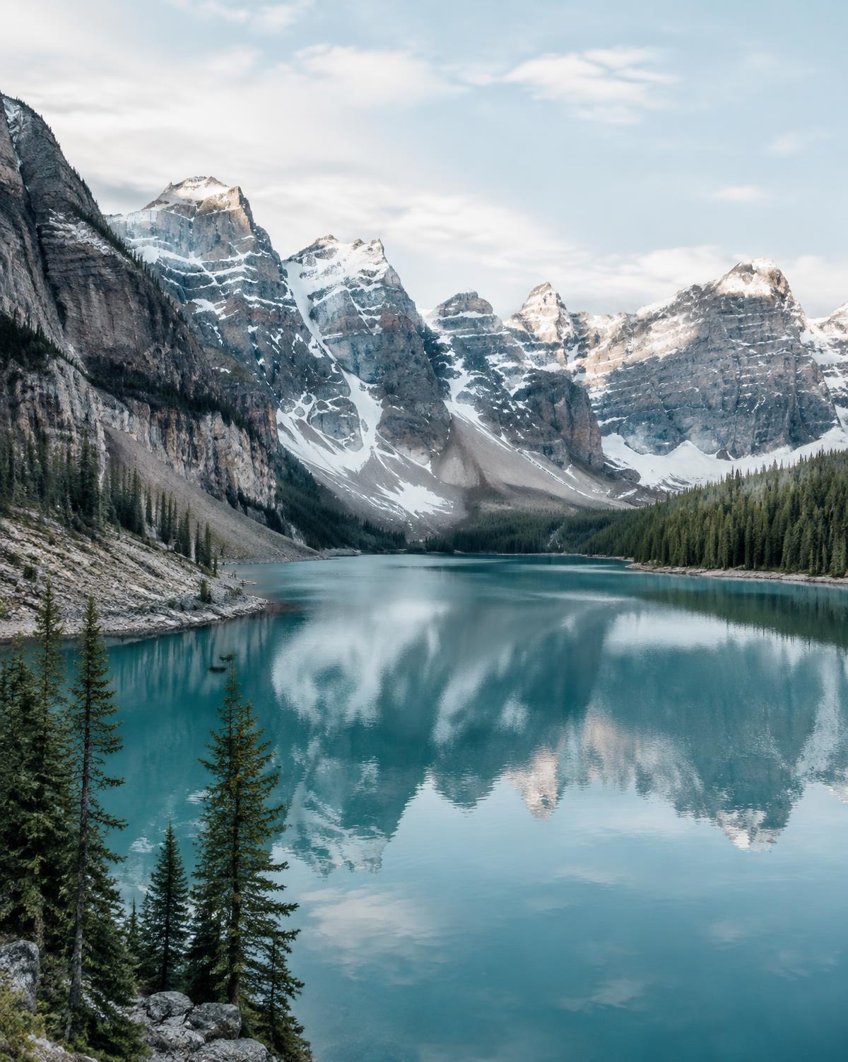 Turquoise glacial lake below snow-dusted peaks in the Canadian Rockies at sunrise